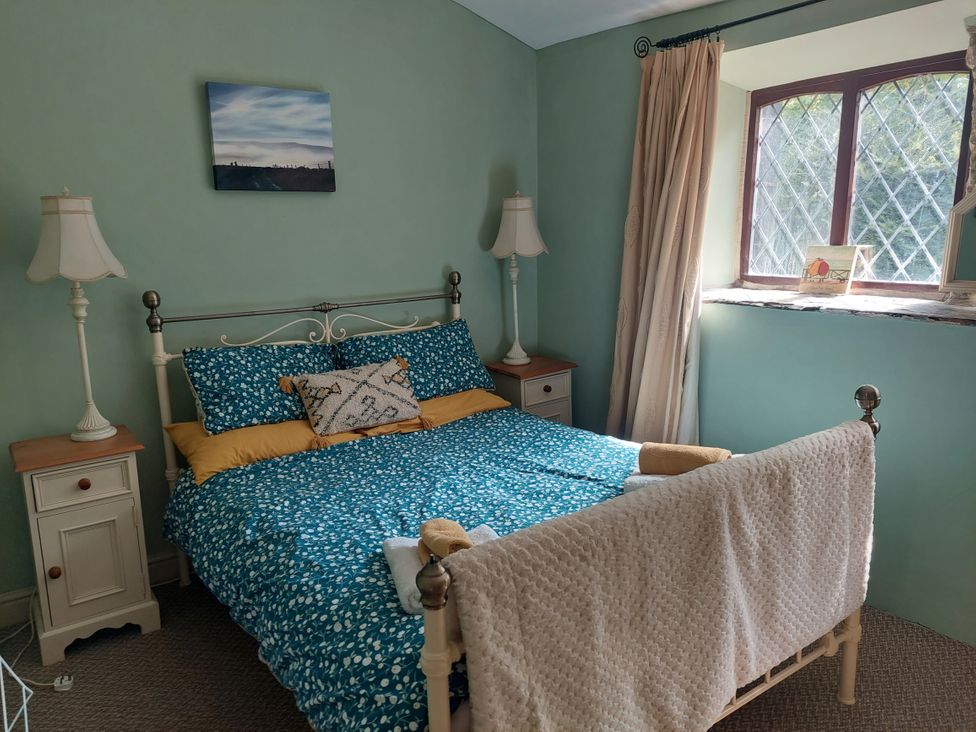A bedroom with a bed and bedside tables at Pet-friendly cottage with walks from the door
