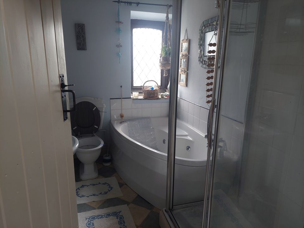 A bathroom with a bathtub, toilet, and a shower at Pet-friendly cottage with walks from the door