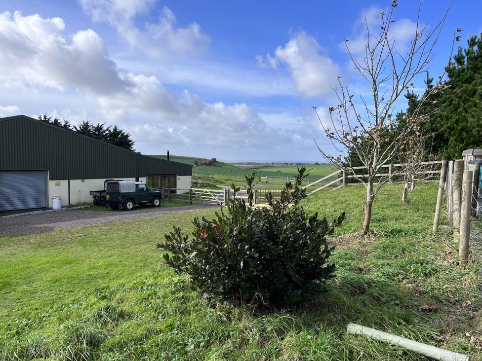 A building and vehicle in a field with a tree at tbc