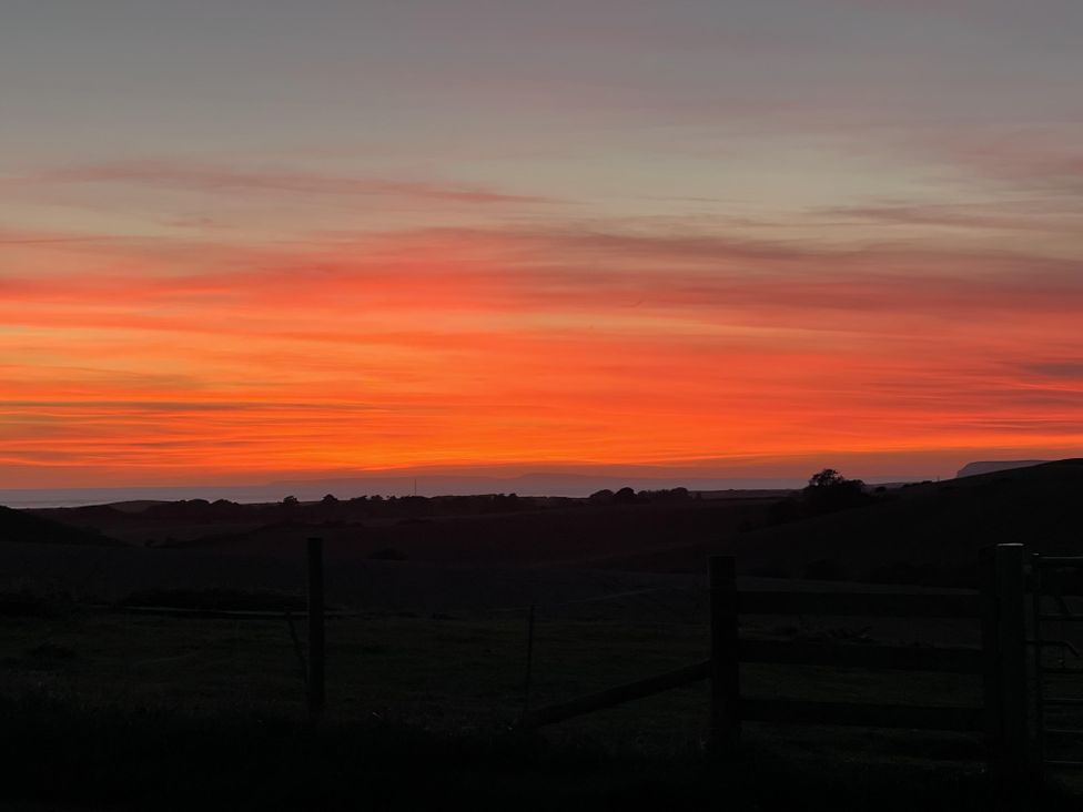 A sunset with orange and pink colors over rolling hills at tbc