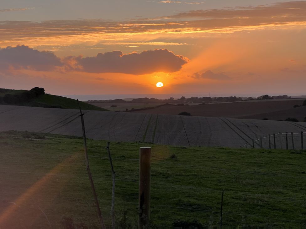 A sunset over fields with a fence at tbc in 