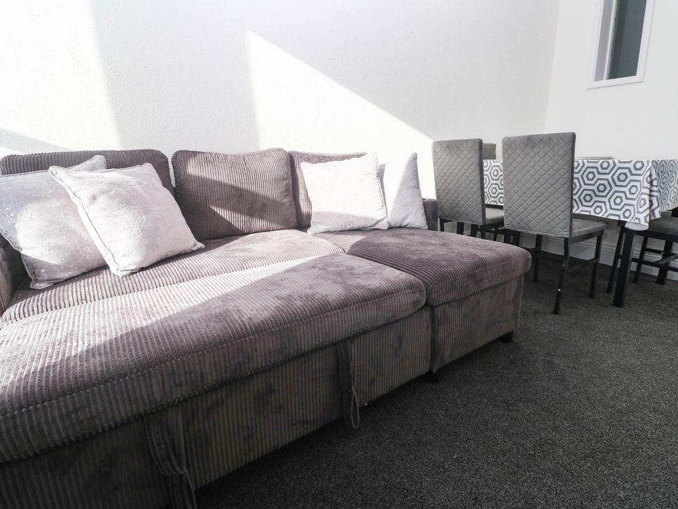A living room with a sofa and dining area at Flat 2 Penzance
