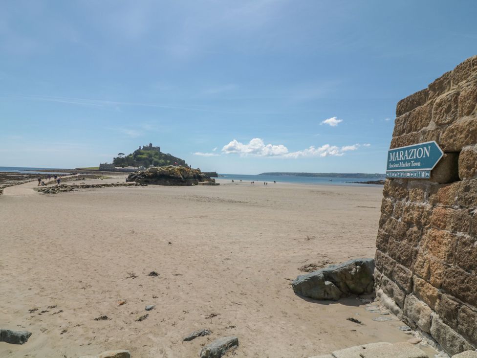 A beach with a view of an island and sign at Marazion in Penzance