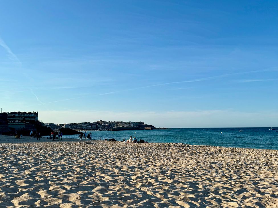 A beach scene with people and buildings at Seafront Soliel in Penzance