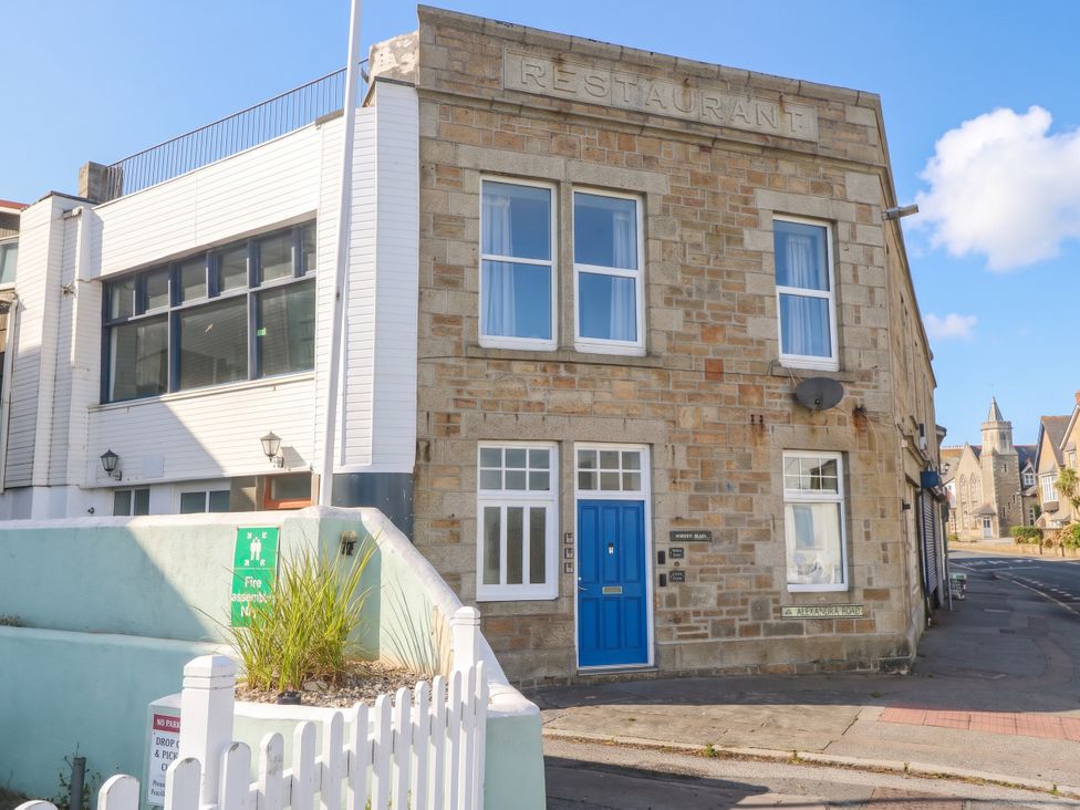 A restaurant building with a blue door and windows at Seafront Soliel in Penzance
