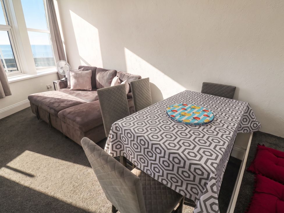 A living room with a couch and dining table at Seafront Soliel in Penzance