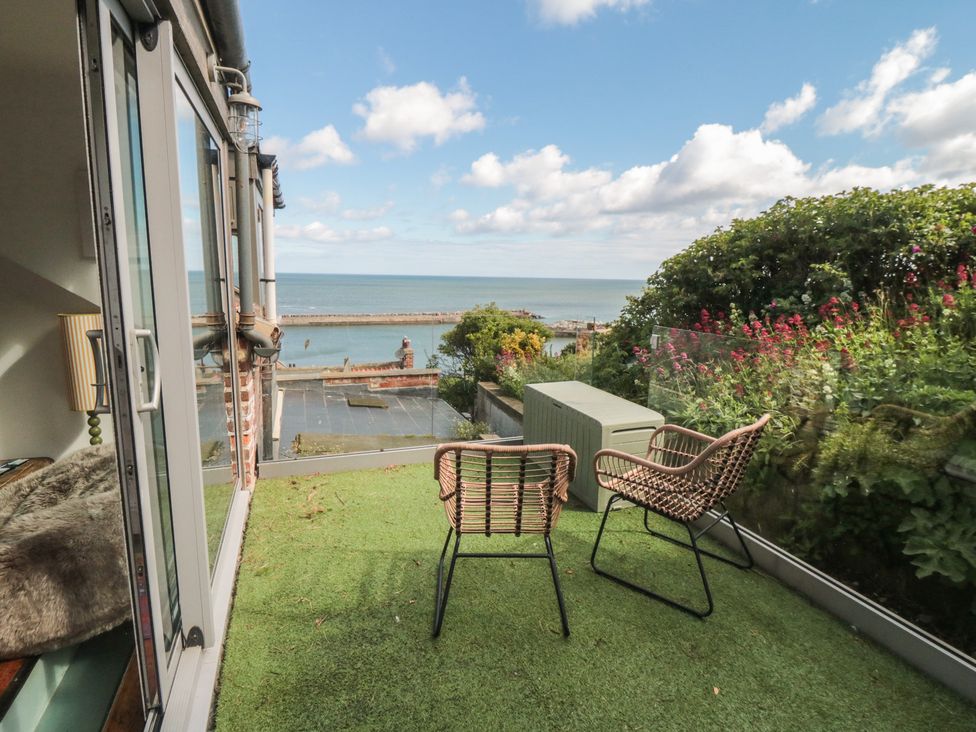 A balcony with chairs and a table overlooking the sea at Hillsover in Saltburn-by-the-Sea