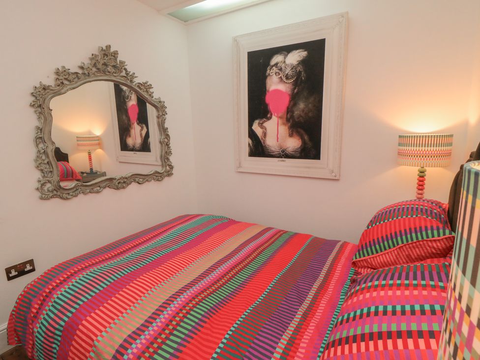 A bedroom with a bed, lamp, mirror, and wall art at Hillsover in Saltburn-by-the-Sea