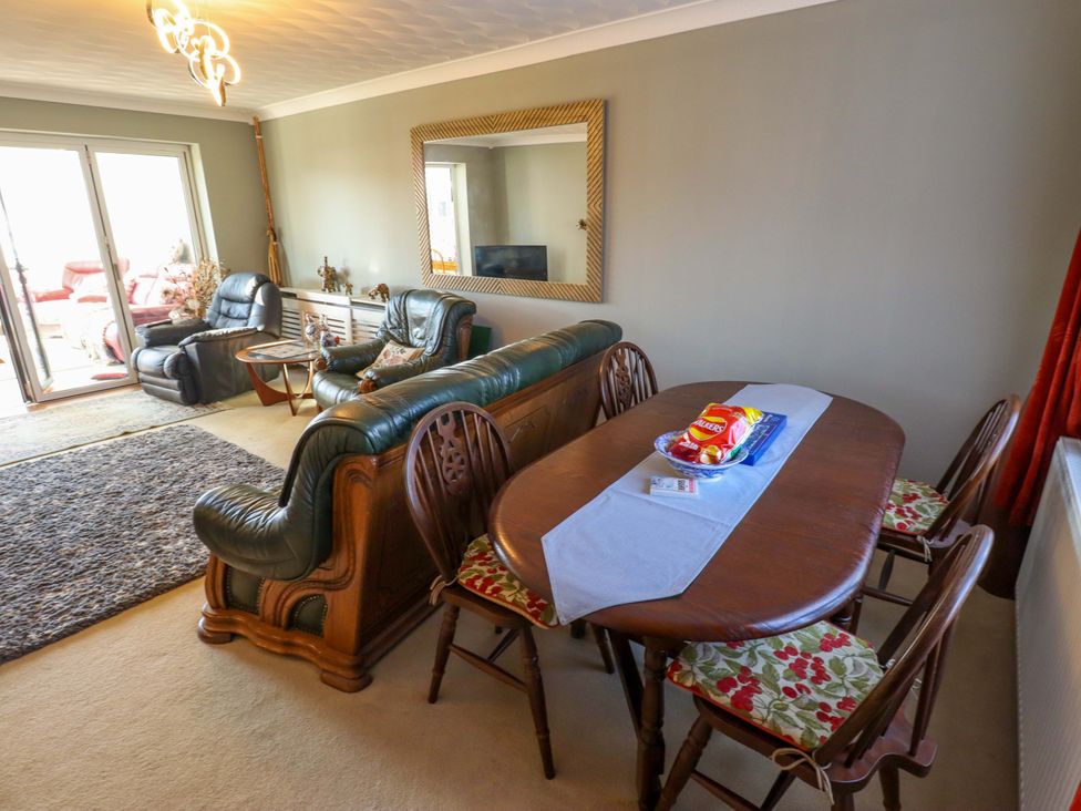 A living room with a sofa, dining table, and television at Seascape in Hunstanton