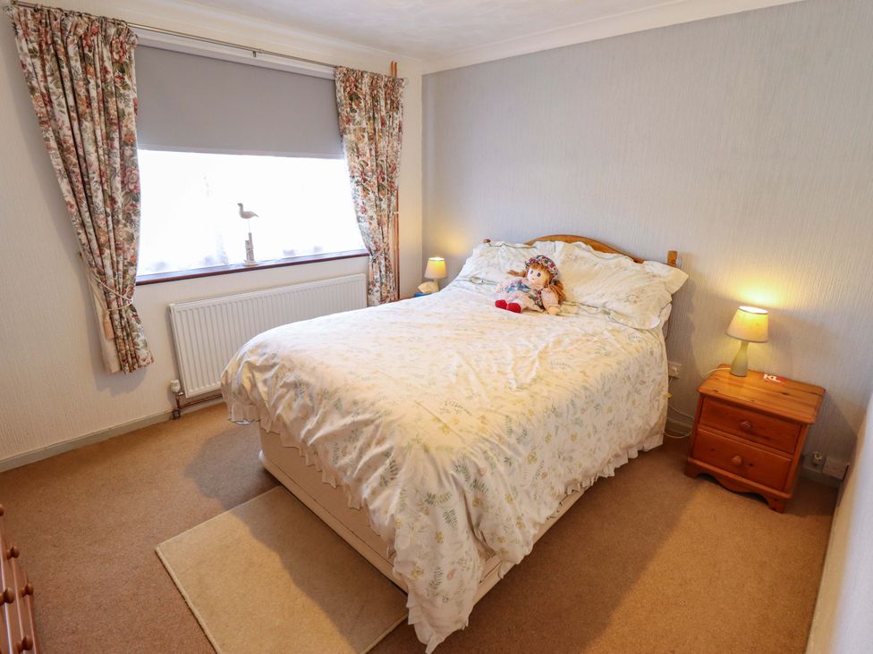 A bedroom with a bed and doll on it at Seascape in Hunstanton