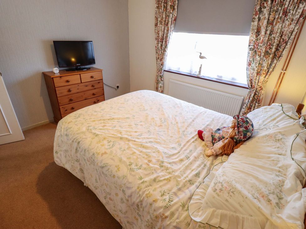 A bedroom with a bed and television at Seascape in Hunstanton