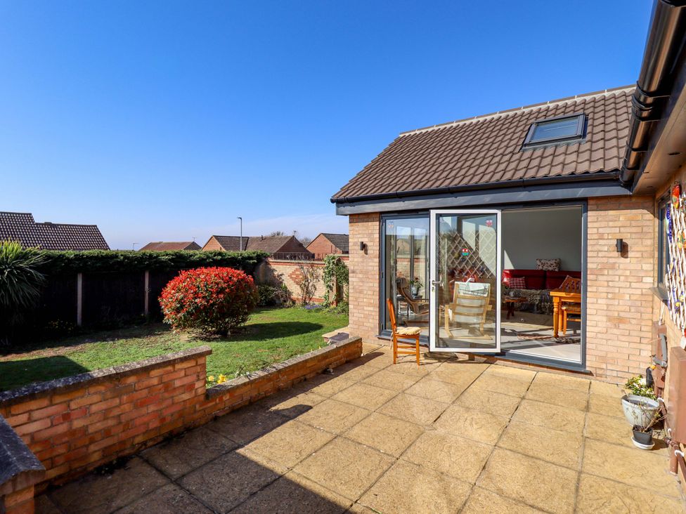 A garden with a patio and glass door at Seascape in Hunstanton