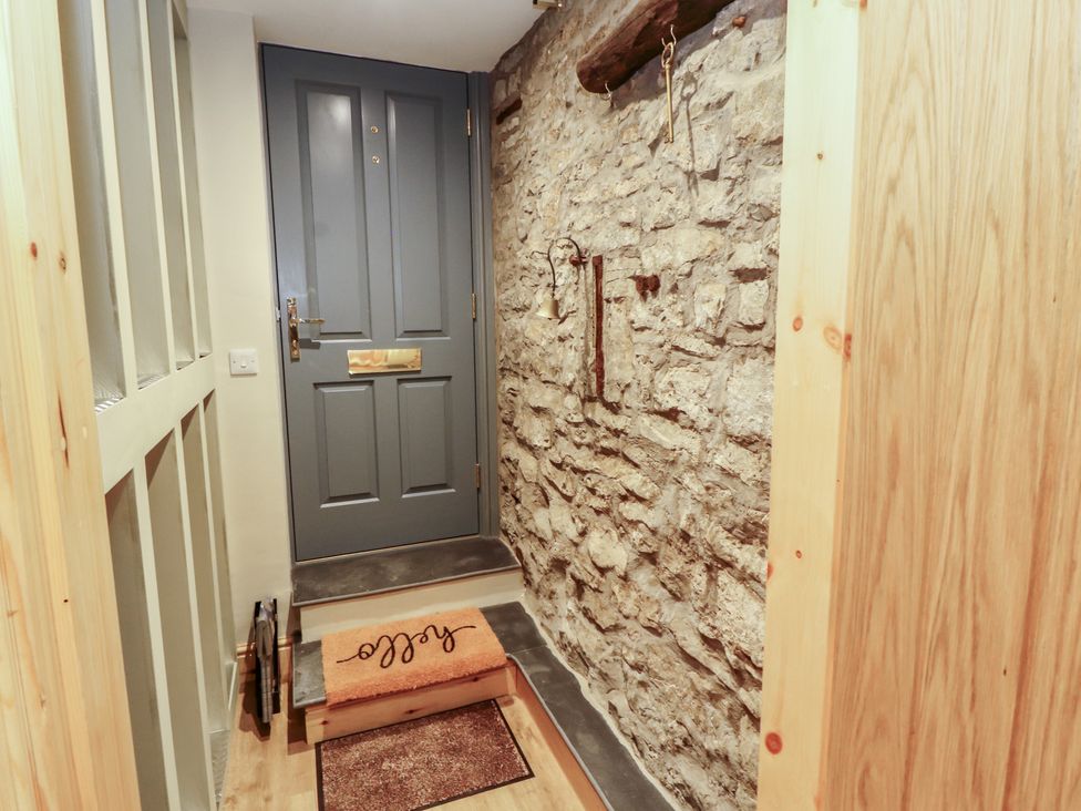 A hallway with a front door and stone wall at The Old Bakehouse in Kendal