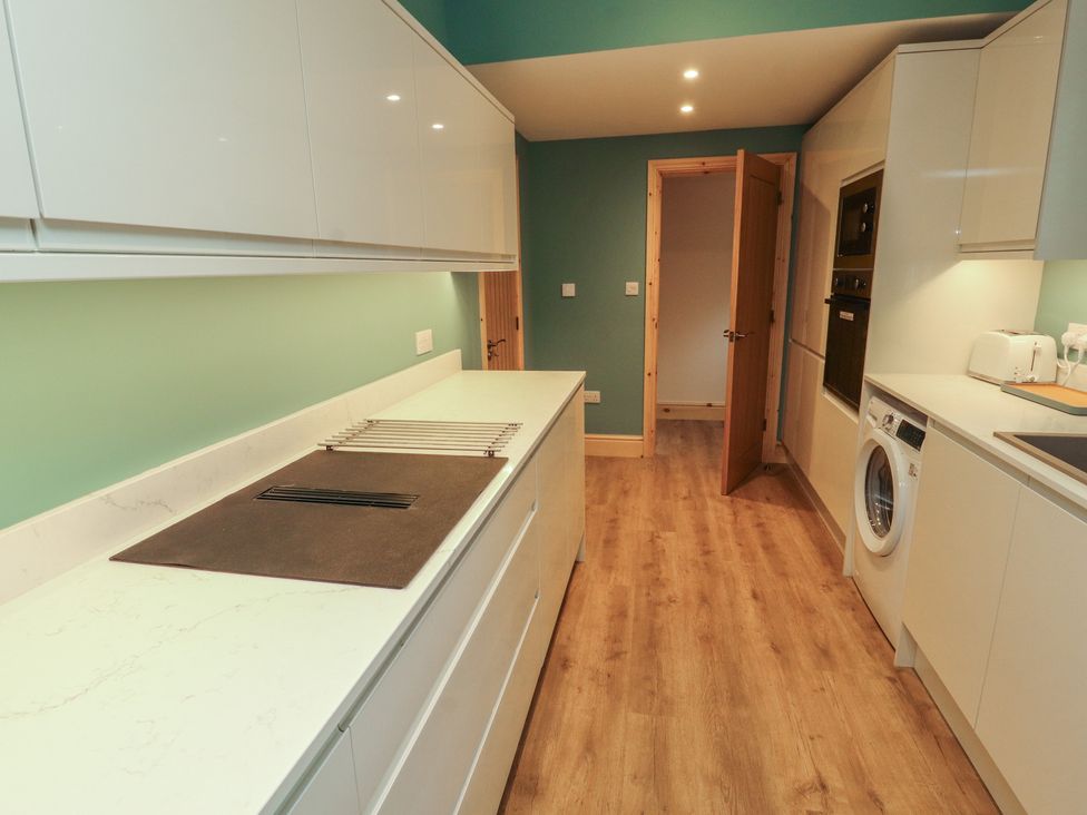 A kitchen with white cabinets and appliances at The Old Bakehouse in Kendal