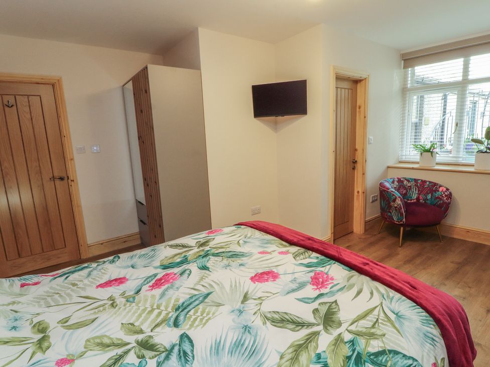A bedroom with a bed and TV on the wall at The Old Bakehouse in Kendal