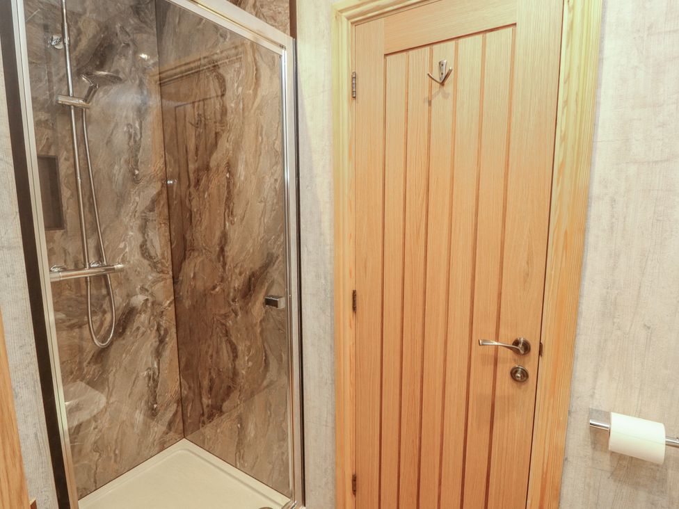 A bathroom with a shower and wooden door at The Old Bakehouse in Kendal