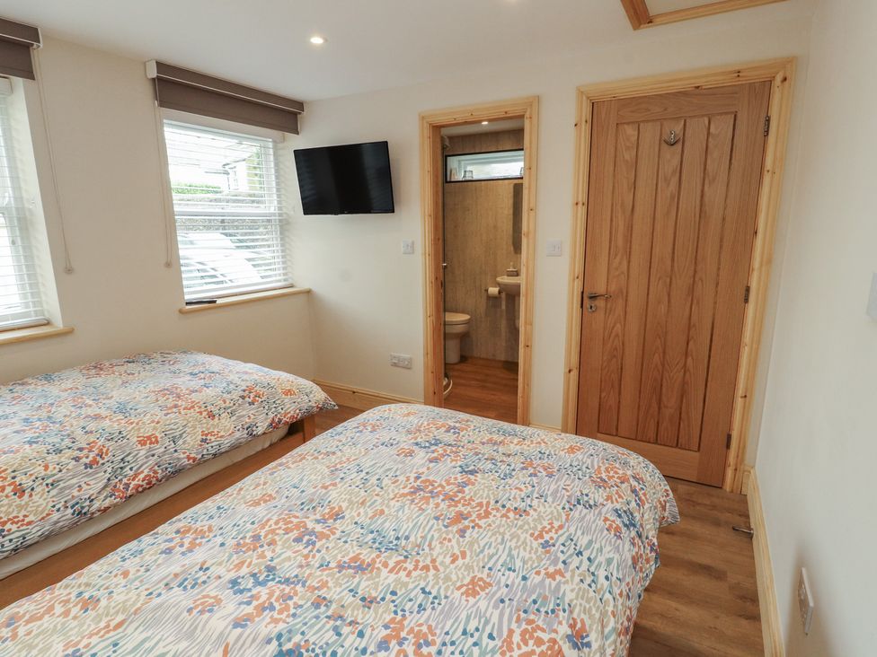 A bedroom with two beds and a bathroom door at The Old Bakehouse in Kendal