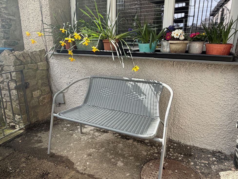 An outdoor seating area with a bench and flower pots at The Old Bakehouse Kendal