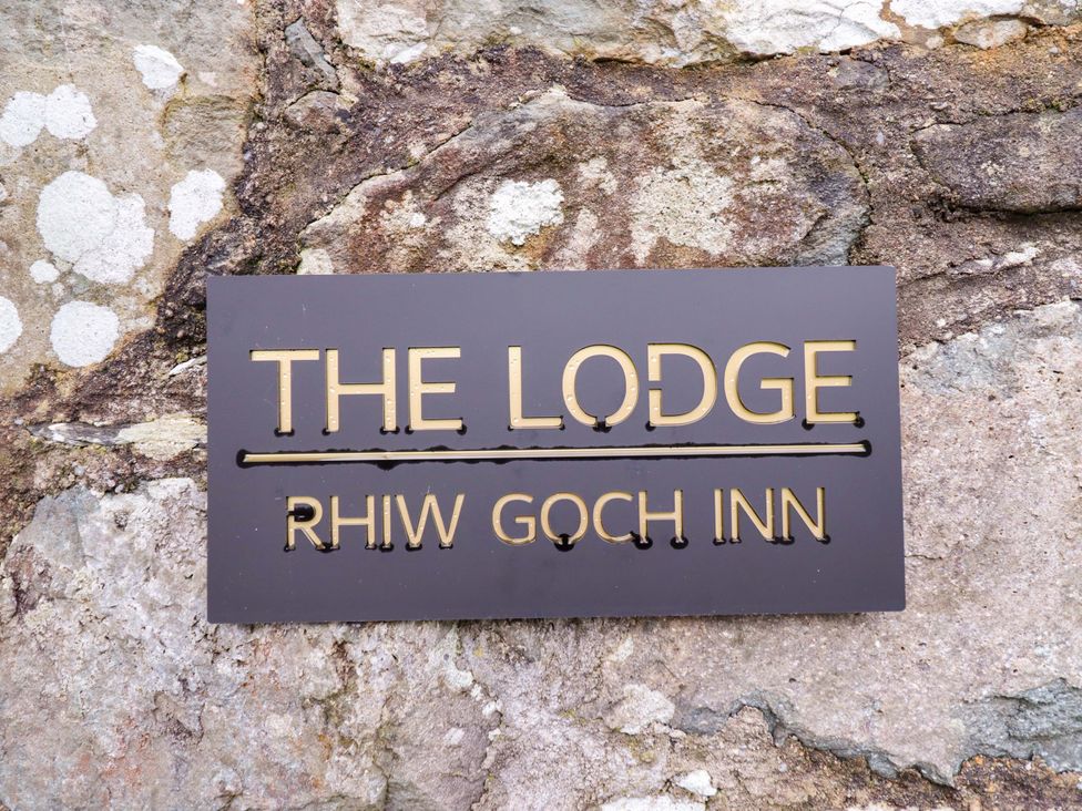 A sign for The Lodge at Rhiw Goch Inn on a stone wall in Snowdonia National Park
