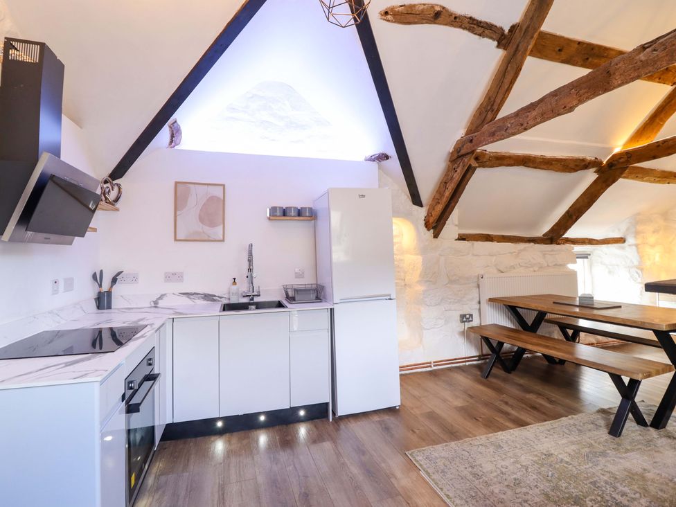 A kitchen with a stove and dining table at The Lodge House at Rhiw Goch Inn in Snowdonia National Park