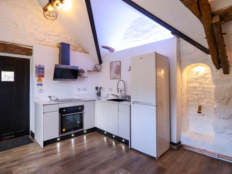 A kitchen with cabinets, stove, sink, and fridge at The Lodge House at Rhiw Goch Inn in Snowdonia National Park