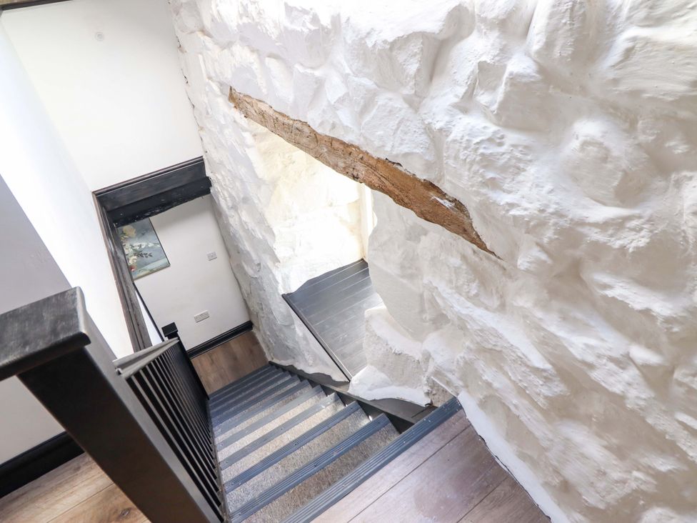 A staircase with a wooden handrail and white walls at The Lodge House at Rhiw Goch Inn Snowdonia National Park