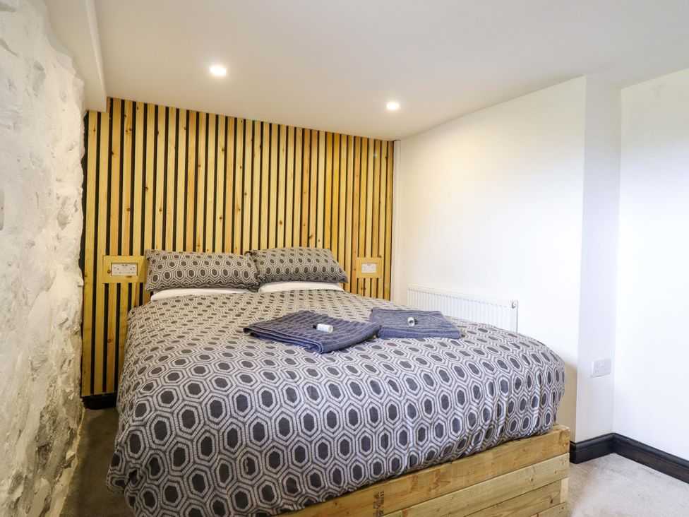 A bedroom with a bed and wooden wall at The Lodge House at Rhiw Goch Inn Snowdonia National Park