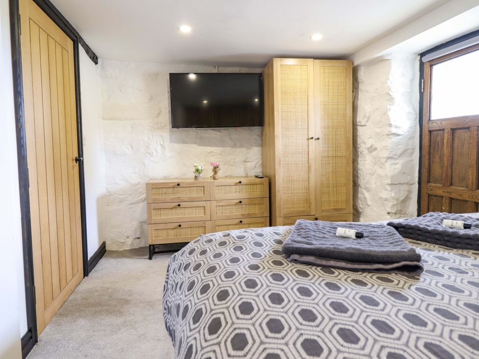 A bedroom with a TV, wardrobe, and drawer unit at The Lodge House at Rhiw Goch Inn Snowdonia National Park