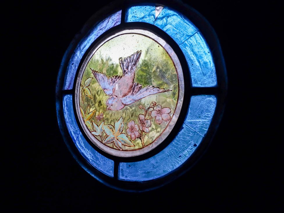 A stained glass window with a bird and flowers at The Lodge House at Rhiw Goch Inn in Snowdonia National Park