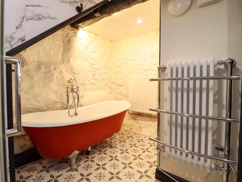 A bathroom with a bathtub and radiator at The Lodge House at Rhiw Goch Inn in Snowdonia National Park