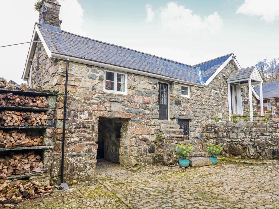 A stone building with woodpile and steps at The Romantic Hideaway at Rhiw Goch Inn in Snowdonia National Park