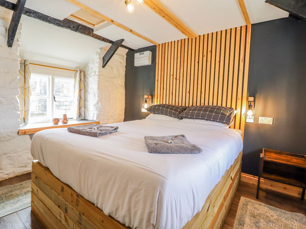 A bedroom with a wooden bed and window at The Romantic Hideaway at Rhiw Goch Inn Snowdonia National Park