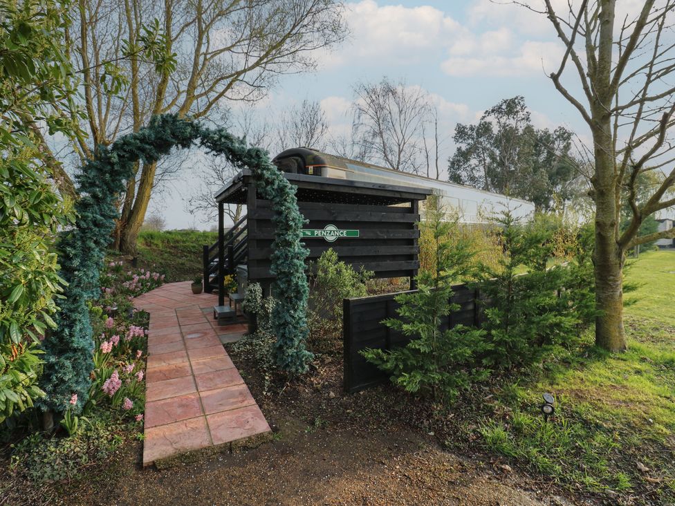 An outdoor view of a railway carriage entrance at Penzance Railway Carriage 1 with hot tub in Ely