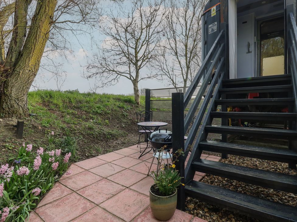 An outdoor area with stairs, table, and flowers at Penzance Railway Carriage 1 with hot tub in Ely