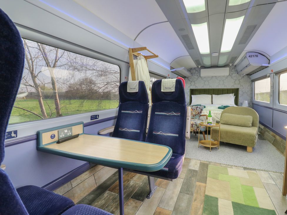 A living room area with seating and a bed at Penzance Railway Carriage 1 with hot tub in Ely