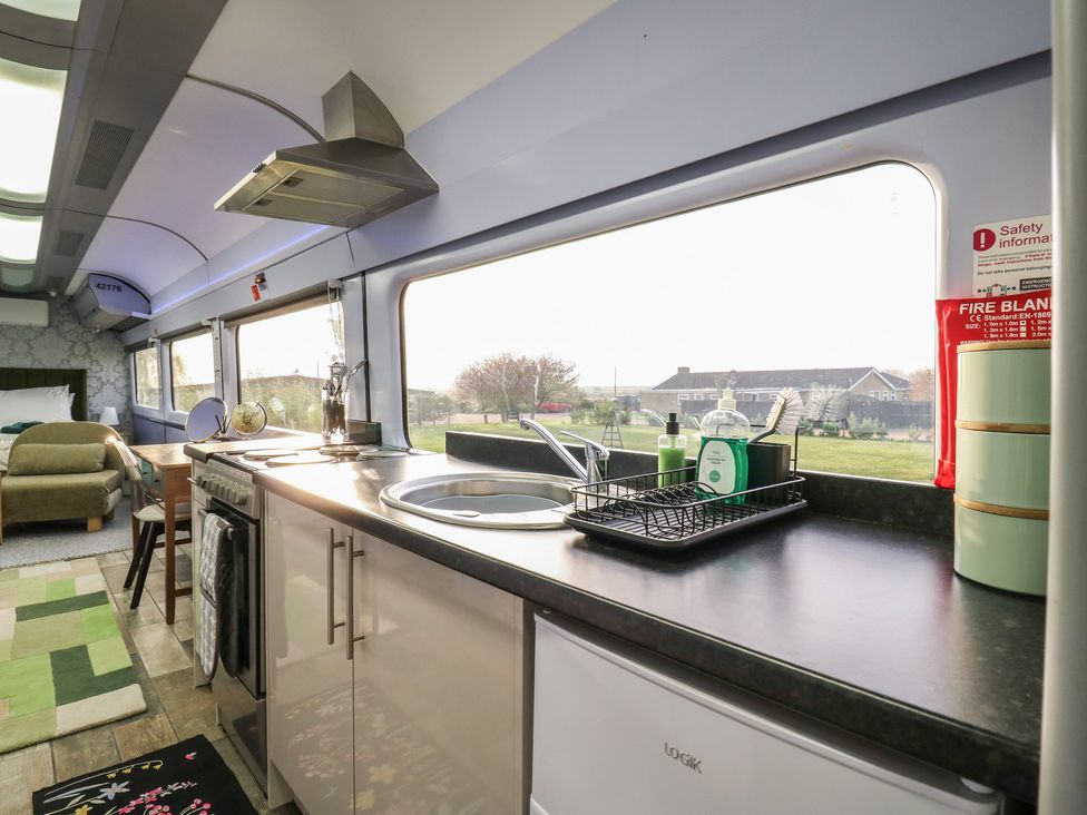 A kitchen area with a sink and stove at Penzance Railway Carriage 1 with hot tub, Ely