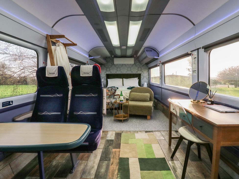 A living room with seats and a table at Penzance Railway Carriage 1 with hot tub, Ely