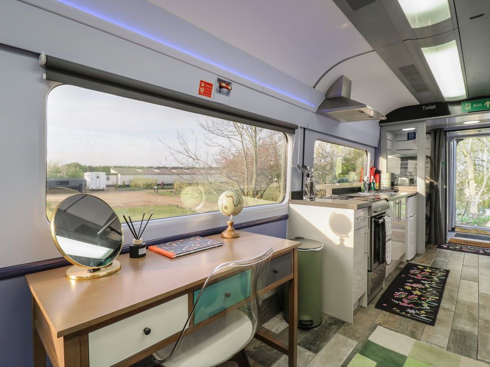 A kitchen with a desk and cooking area at Penzance Railway Carriage 1 with hot tub in Ely