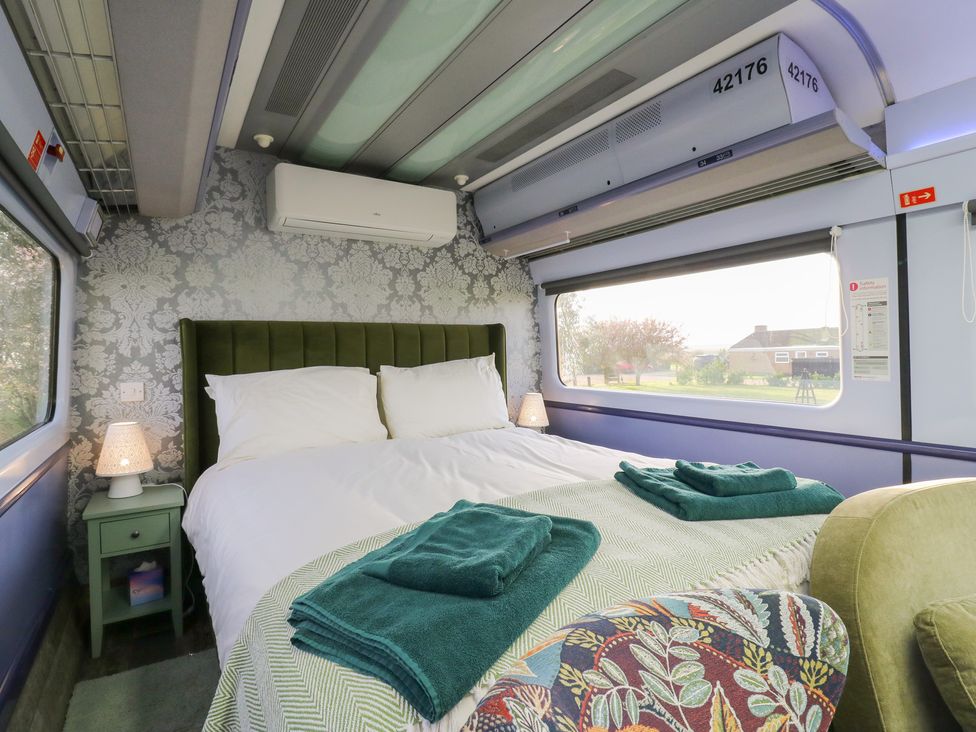 A bedroom with a bed and bedside table at Penzance Railway Carriage 1 with hot tub in Ely
