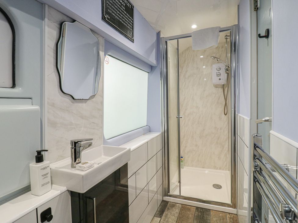 A bathroom with a sink and shower at Penzance Railway Carriage 1 with hot tub in Ely