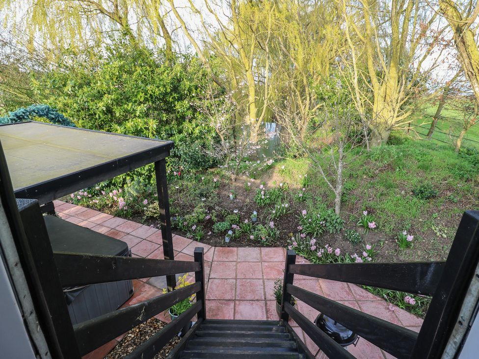 A garden with flowers and a table near stairs at Penzance Railway Carriage 1 with hot tub, Ely