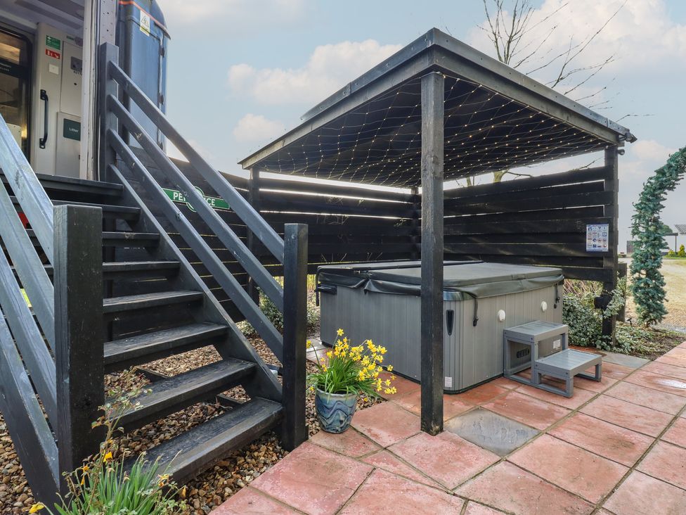 An outdoor hot tub under a shelter at Penzance Railway Carriage 1 with hot tub Ely