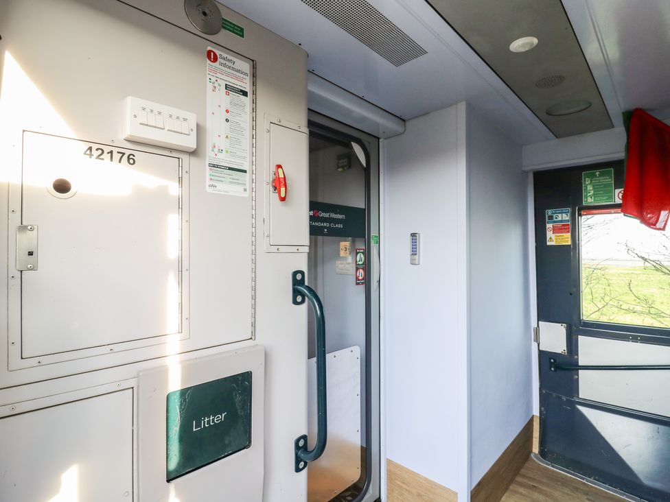 A train corridor with doors and safety signage at Paddington Railway Carriage 2 with hot tub, Ely