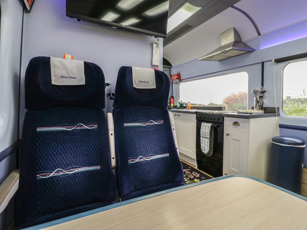 A train carriage with seats and kitchen area at Paddington Railway Carraige 2 with hot tub, Ely