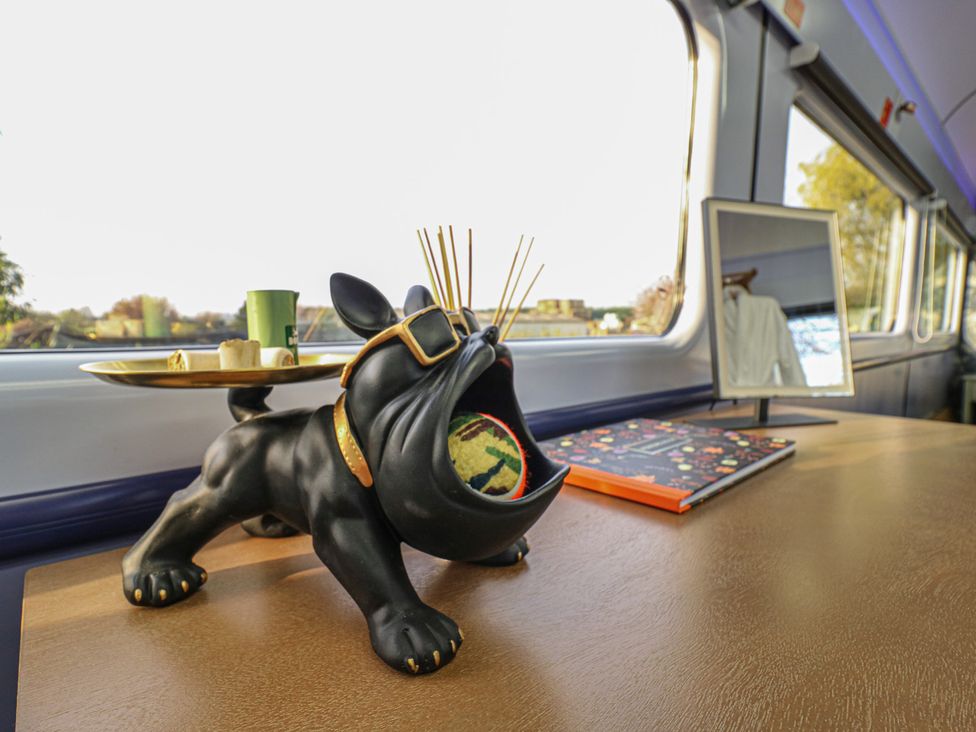 A dog sculpture holding a plate on a table at Paddington Railway Carraige 2 with hot tub in Ely