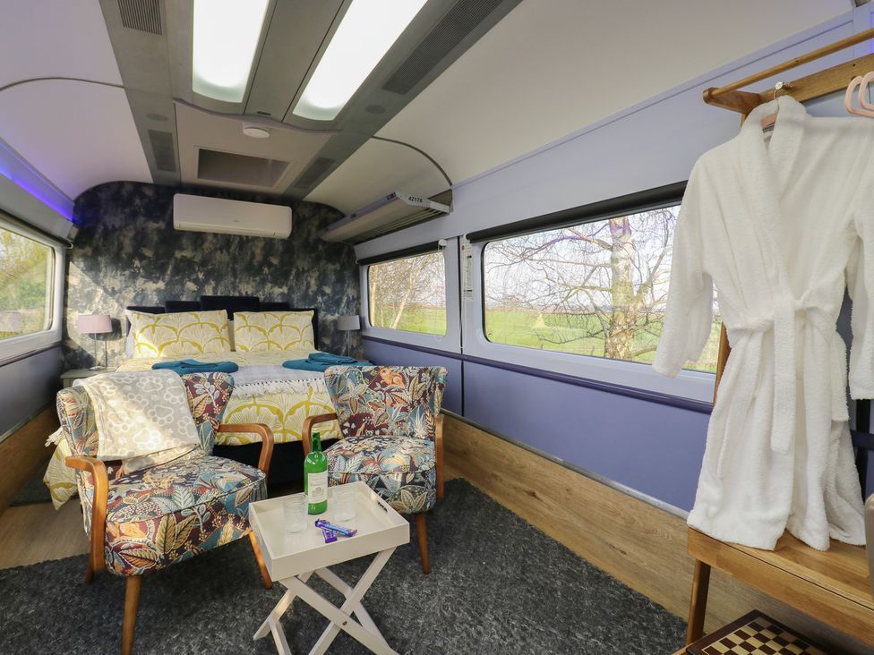 A bedroom with a bed and chairs at Paddington Railway Carraige 2 with hot tub in Ely