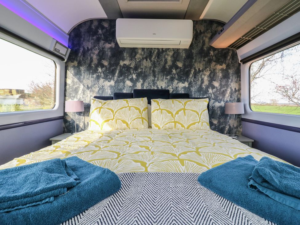 A bedroom with a bed and bedside lamps at Paddington Railway Carraige 2 with hot tub in Ely