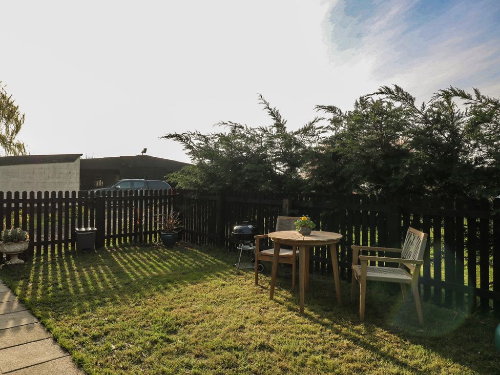 A garden with a table, chairs, and grill at Paddington Railway Carraige 2 with hot tub, Ely