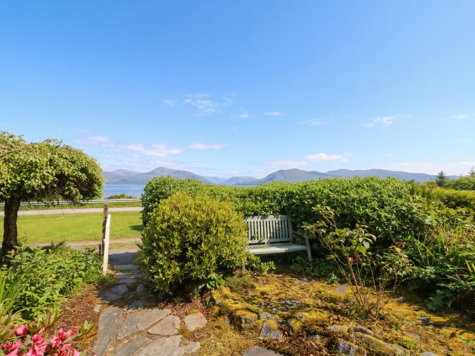 A view of a garden with a bench and mountains at 4 Whiterow Kentallen near Ballachulish