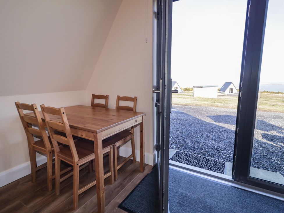 A dining area with a table and chairs at Cabin 6 An Mhucais in Gortahawk